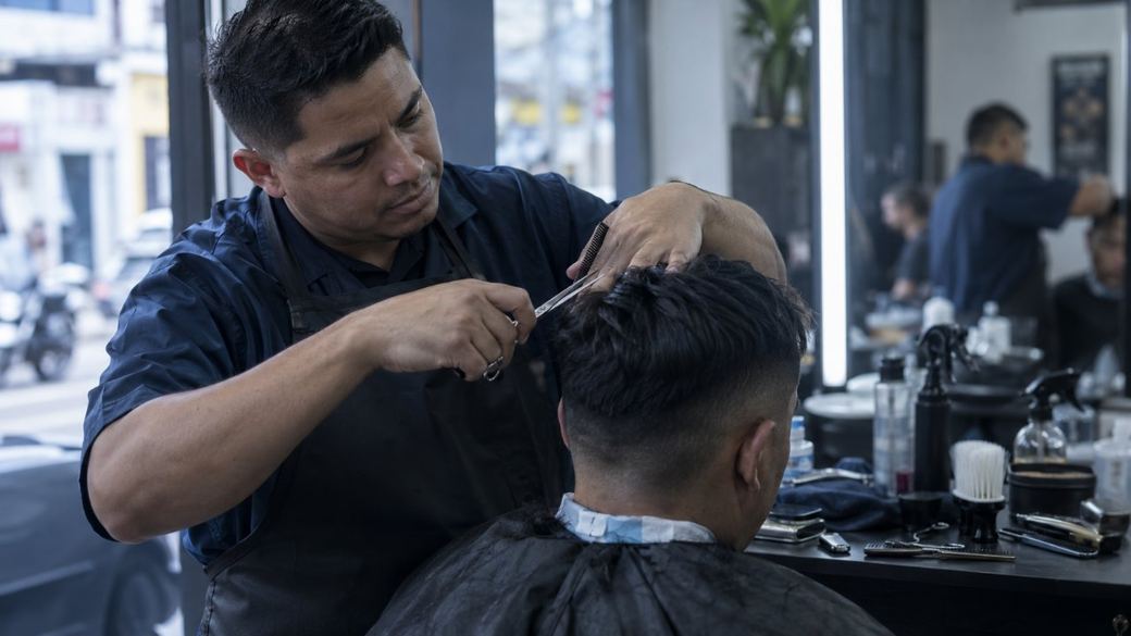 Un barbero corta el cabello de un cliente con tijeras y peine en una barbería de barrio